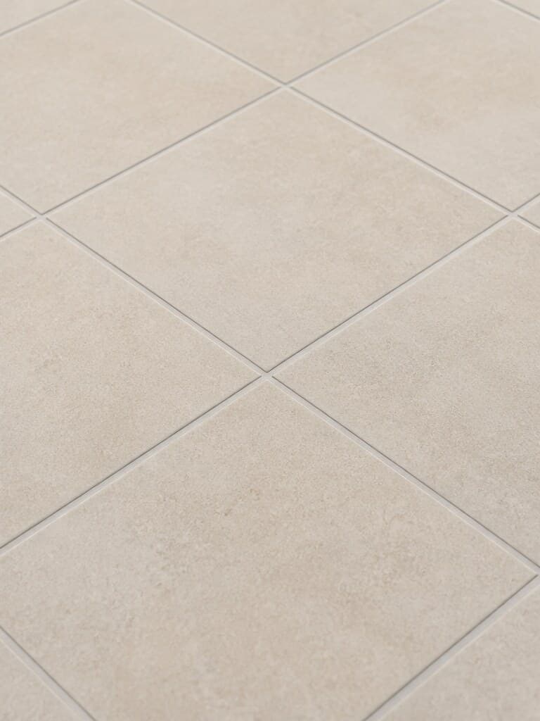 Illustrative close view of ivory tile and light-gray grout.